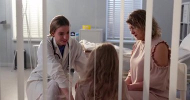 Sıcak ve ilgili bir hastane ortamında, bir doktor genç bir hasta ve annesiyle sevgiyle ilgilenir.