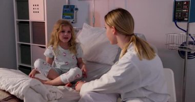 Hastane odasında şefkatli bir hemşireyle sohbet eden bir çocuğu canlandıran iç açıcı bir sahne var.