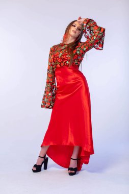 Kendine güveni tam bir manken canlı ve göz alıcı bir çiçek desenli bluzla göz kamaştırıcı bir kırmızı saten etekle poz veriyor.