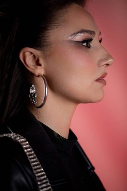 Modern makyaj ve şık aksesuarları canlı ve canlı bir arkaplanda sergileyen şık bir profil çekimi.