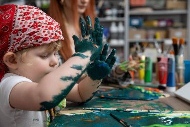 Canlı ve parlak renklerle dolu keyifli bir resim seansına dalmış genç bir çocuk.