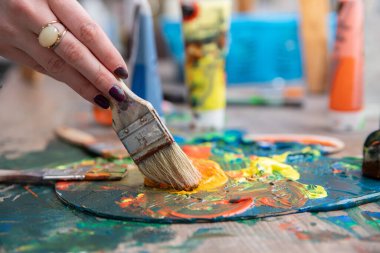 Bir el ustalıkla fırçayı tutar, bir sanat stüdyosundaki palette canlı boyalar karıştırır, yaratıcılık sergiler.