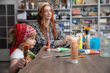 Bir anne ve kızı mutlu bir şekilde renkli bir sanat projesiyle meşguller, yaratıcılıklarını ve bağlarını geliştirmek için.