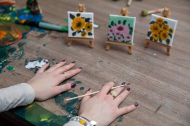 İlham verici bir sanat sahnesi yetenekli elleri titizlikle küçük tuvallere güzel çiçek desenleri çiziyor.