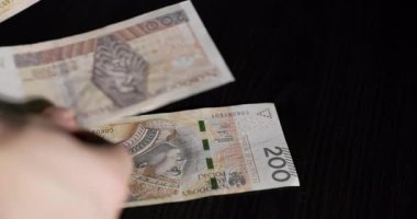 Karanlık bir yüzeyde banknotları sayan bir kişi, ticaret ve ekonomideki mali işlemleri vurguluyor.
