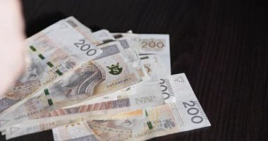 Kırsal ahşap bir yüzey üzerindeki banknotları sayarak dinamik hareketlerde para birimini gösteren ellerin yakınlaşması