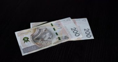 Lehçe 200 z banknot sayan bir el karanlık bir masanın üstünde, mali işlemleri gösteren