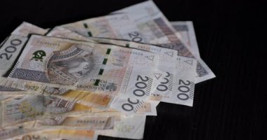Detaylı bir yakın çekim görünümü, parlak siyah bir yüzeye düzgünce istiflenmiş 200 banknot sergiliyor.