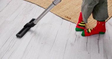 Renkli çoraplar içindeki genç bir çocuk neşeli bir temizlik tarzı sergileyerek parlak bir zemini süpürmekten mutluluk duyar.