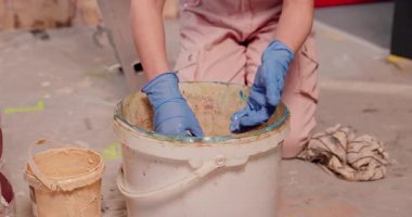 Bir birey boya renklerini bir kovada karıştırıyor, ev projeleri için eğlenceli DIY işçiliği sergiliyor