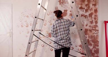 Yenilikçi bir birey, boş bir duvarı merdiven ve yaratıcı tasarımlar kullanarak çarpıcı bir sanata dönüştürür.