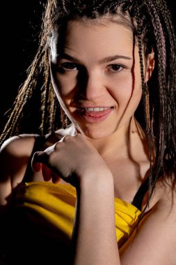 Genç bir kadın, kendine güvenini ve tarzını karmaşık saç stili ve çarpıcı ışıklandırmada canlı kıyafetleriyle sergiliyor..