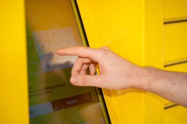 Parlak sarı bir büfedeki dokunmatik ekrana dokunan bir el gündelik hayatta modern teknolojiyi gösteriyor.