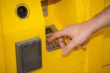 Bir insan eli, modern bankacılık teknolojisinin rahatlığını gösteren, parlak sarı bir ATM ile etkileşim halindedir.