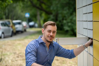 Genç bir adam rahat ve rahat tarzını sergileyerek canlı bir şehir bölgesinde, bir posta kutusunun yanında güven içinde poz veriyor.