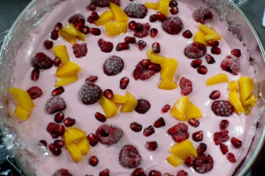 Lezzetli bir ikram için taze ahududu, mango ve nar tohumlu kremalı yoğurt kasesi.