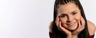 Neşeli genç bir kadın zarif pozlar veriyor, güzel örgülü saçlarını ve neşe dolu ifadesini sergiliyor.