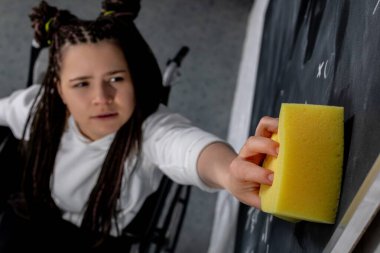 Genç bir kadın, bir süngerle canlı karatahta sanatı yaparak yaratıcılığını sergiliyor. Kararlılığını gösteriyor.