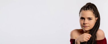 Saçları güzel örülmüş genç bir kadın özgüvenle poz veriyor, eşsiz stili ve hayat dolu kişiliğini sergiliyor.