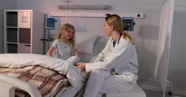 Bir hastane odasında, kendini adamış bir hemşire genç bir hastayla samimi bir şekilde iletişim kurar.