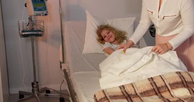 İlgili bir hemşire, hastane yatağında yatan genç bir kıza bakar. Burada kaldığı süre boyunca sıcaklık ve konfor sağlar.