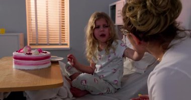 Bir kız doğum gününü neşeli bir hastane odasında pastayla kutluyor. Sevdikleriyle mutlu anların tadını çıkarıyor.