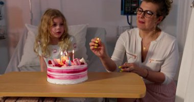 Bir hastane ortamında paylaşılan, çok güzel dekore edilmiş bir pasta ve neşeli bir çocuğun yer aldığı iç açıcı bir doğum günü anı.