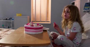 Neşeli bir hastane ortamında iyileşirken genç bir kız lezzetli bir doğum günü pastasının tadını çıkarıyor.