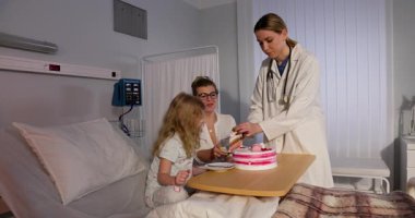 Hastanede, şefkatli bir doktor ve sevgi dolu bir aile bunu pastayla kutluyor, iyileşme sürecinde neşe ve umut besliyor.