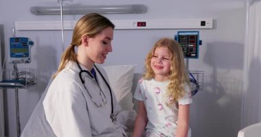 Bir doktor, genç bir hastayla neşeli ve olumlu bir şekilde ilgilenir. Parlak bir hastane ortamında.