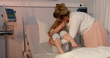 Hastane ortamında bir anne ve çocuğu arasında samimi bir etkileşim, sevgi ve ilgi göstergesi.