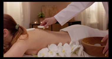 Rahatlatıcı yağlar ve taze çiçekler kullanılarak lüks bir masaj yapılan sakin bir spa sahnesi, derin rahatlama için ideal.