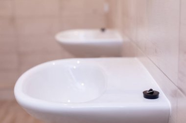Çağdaş bir banyo ortamındaki parlak beyaz lavabo temizliği ve işlevselliği vurguluyor..