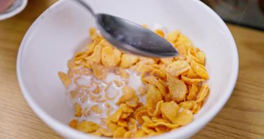 Keyifli ve rahatlatıcı bir kase gevrek gevrek ve taze süt sıcacık ve sıcacık bir ortamda tadını çıkarıyor.