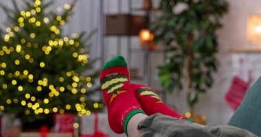 Şenlikli çoraplar giyip, güzel süslenmiş Noel ağacının yanında dinlenerek, neşeli Noel ruhunu yakalıyor.