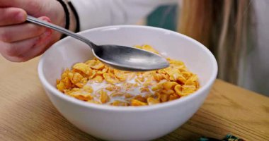 Mısır gevreği ve sütle dolu bir kâsenin hoş bir yakın çekimi rahatlatıcı bir kahvaltı deneyimi sunuyor.