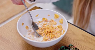 Bir insan, sıcak ve rahat bir kahvaltı sahnesi yaratarak, bol sütlü gevreğin tadını çıkartıyor.