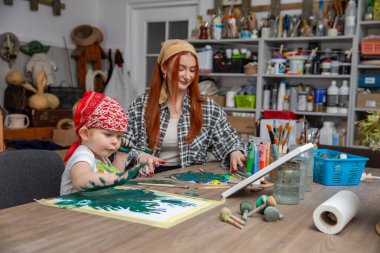 Bir anne ve küçük çocuğu neşeyle renkli sanatlar yaratıyor, yaratıcılıklarını ve aile eğlencelerini sergiliyorlar.