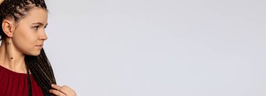 Saçları örgülü, şık bir elbise giymiş ve arka planda küpe takan bir kadının yan profili..