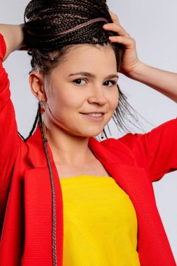 Canlı ve renkli giysiler içinde, kendine özgü örgülü saç stiliyle gururla hava atan şık bir genç kadın.