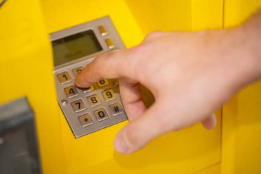 Parlak sarı bir makinede, teknolojiyi ve etkileşimi vurgulayan sayısal tuş takımını ustalıkla kullanan bir el.