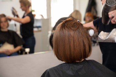 Modern bir kuaför salonunda, çok yetenekli bir kuaför bir müşteri için şık ve şık bir saç stili yaratıyor.