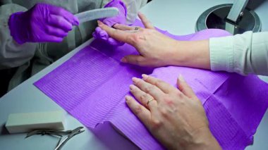 Profesyonel manikür seanslarında tırnak törpüleme ve bakım teknikleri ustalıkla gösterilir, eldivenlerle tamamlanır.