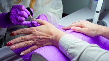 Yakından bakınca, yetenekli bir tırnak teknisyeninin müşterilerine jöle sürdüğü görülüyor.