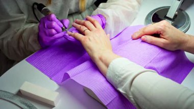 Yetenekli bir tırnak teknisyeni, profesyonel aletleri kullanarak ustalıkla karmaşık tırnak sanatları yaratıyor.