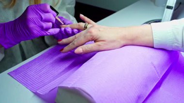 Bir teknisyen, rahatlatıcı bir manikür sırasında canlı tırnak cilası sürerek müşterinin şımartıcı bir deneyim yaşamasını sağlar.