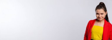 Modayı takip eden genç bir kız, neşe ve enerji saçan neşeli bir gülümseme takınarak kendine güvenerek poz verir.