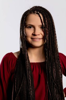Uzun, güzel örgülü saçları olan neşeli genç bir kız. Parlak, canlı kırmızı bir kıyafet giymiş, neşe saçıyor.