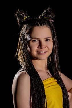 Genç bir kadının canlı portresi örgülü saçları ve neşeli bir ifadesi var. Olumlu ve çekici.