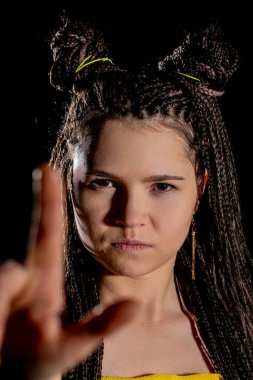 Genç bir kadın, karmaşık örgülü saçlarıyla, özgüven ve yaratıcılığıyla cesur bir poz verir.